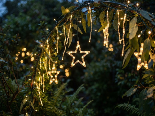 Solar-powered LED Christmas light displays glowing in a garden at dusk