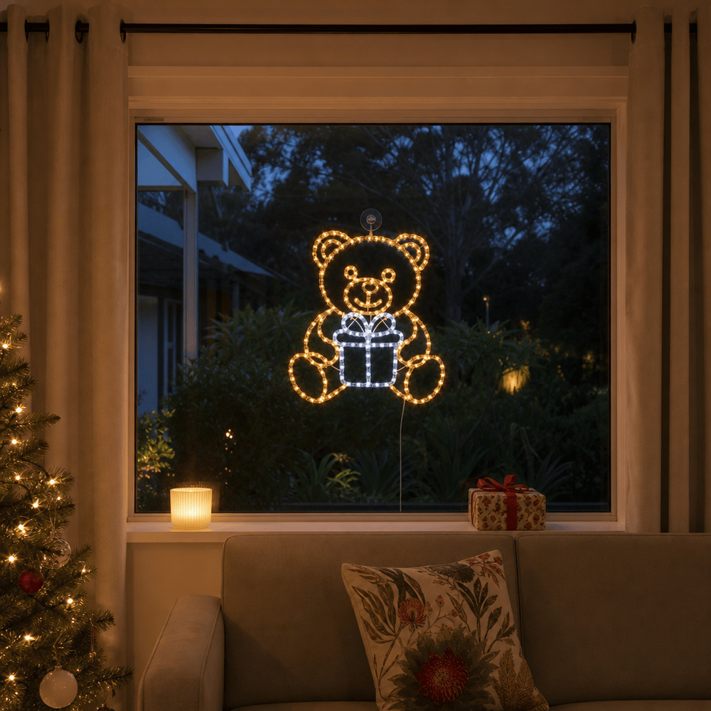 LED Acrylic Bear and Present Motif (42cm) glowing in a living room window at night