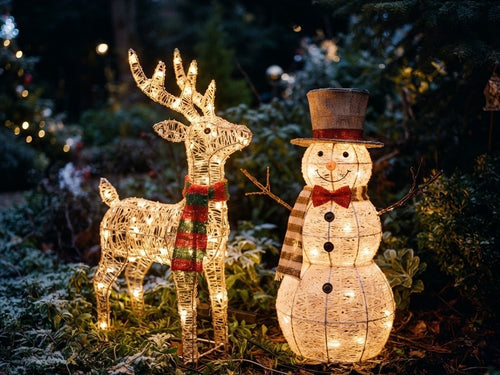 Illuminated solar reindeer and snowman figures in a garden at night